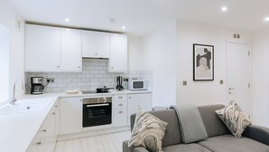 Une cuisine de taille réduite avec des meubles blancs, un four à micro-ondes et une cuisinière.