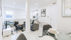 Un salon moderne avec une table à manger en verre, des canapés gris et une table basse.