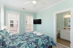Un dormitorio con cama, televisión, baño y ventilador de techo.