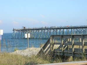 A wooden pier extending into the water with a sandy beach in the foreground. - Clam Shack - Oceanview and waterway view townhome, elevator, pool! (Carolina Beach)