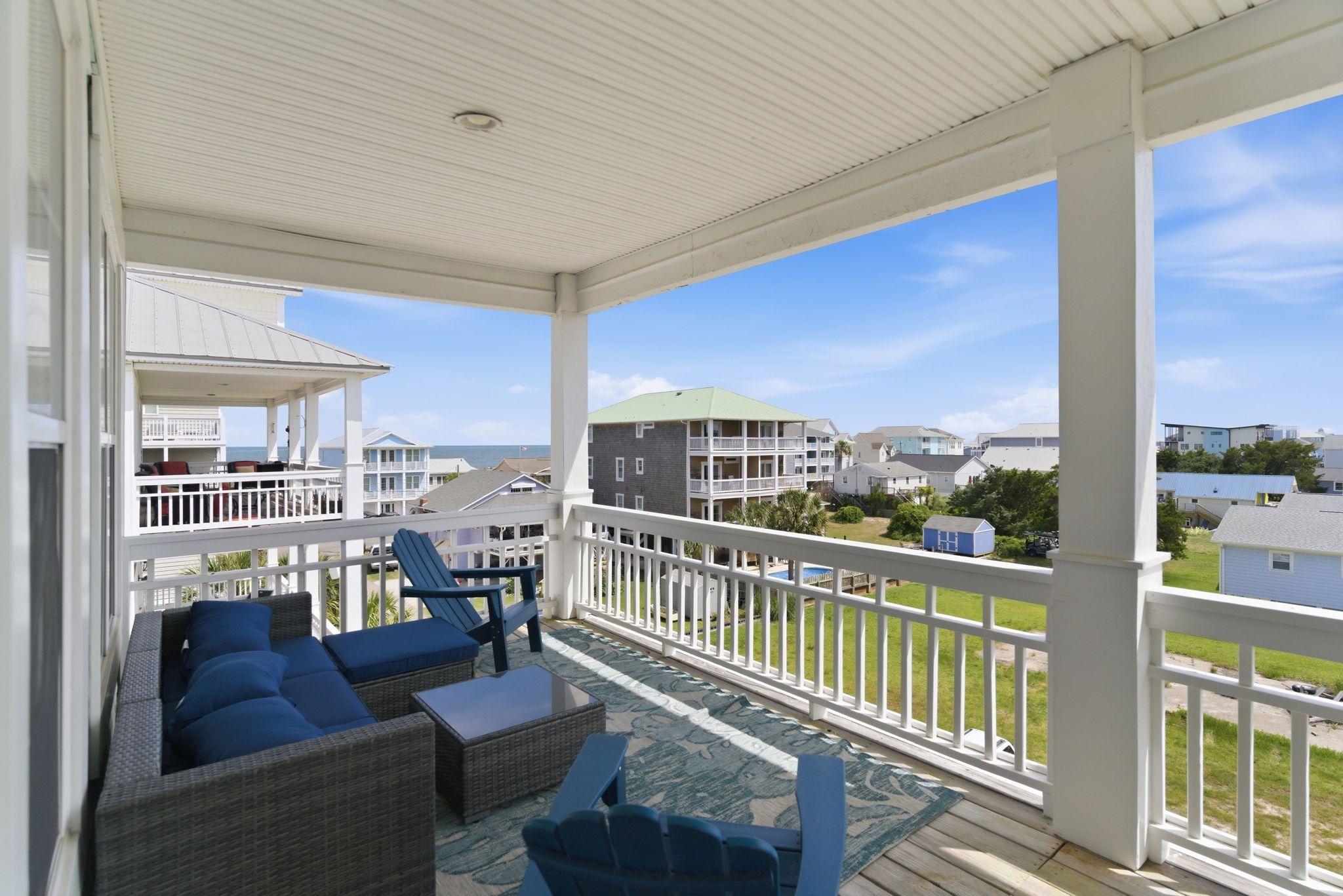 A covered outdoor area with wicker furniture and a view of a residential area.