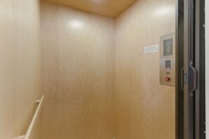 Un ascensor estrecho con un panel de control a la derecha.