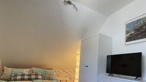 Makuuhuone, jossa on sänky, lipaston päällä oleva televisio ja ovi.