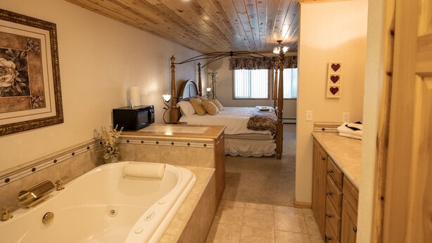 Une chambre avec une grande baignoire, un lit double et une coiffeuse avec un miroir.