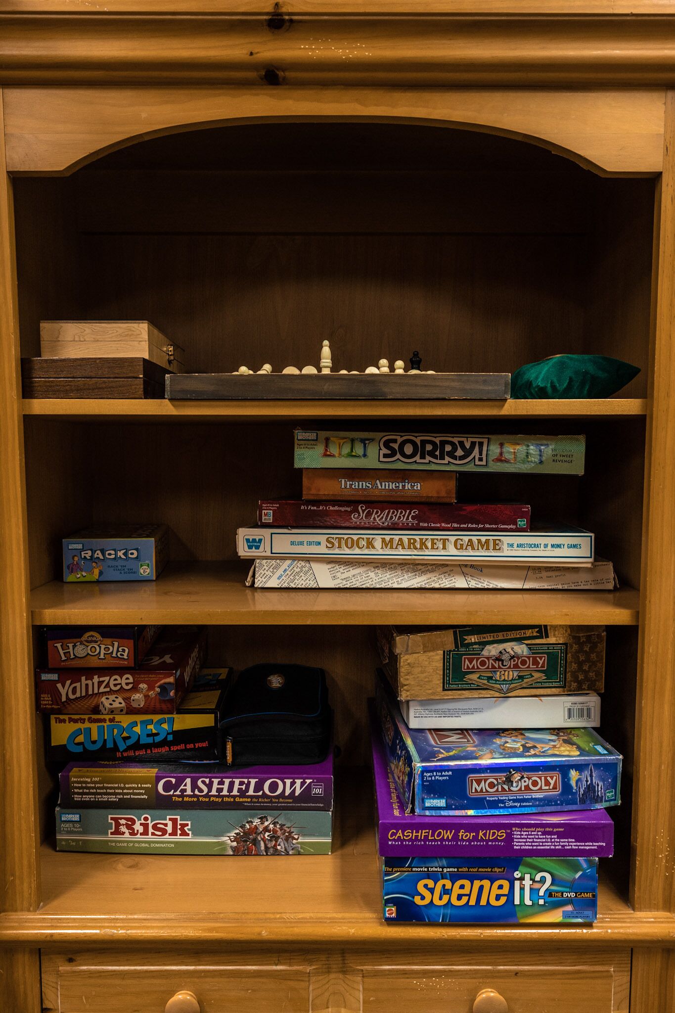 A wooden shelf with various board games stacked on it.