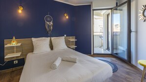 A modern bedroom with a large bed, bedside tables, a dreamcatcher, and a view through a glass door. - Terrasse en ville - Première conciergerie (Montpellier)
