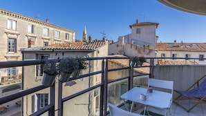 A balcony with a table and chairs, potted plants, and a view of surrounding buildings. - Terrasse en ville - Première conciergerie (Montpellier)
