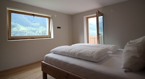 A bedroom with a bed, a window, and a door.