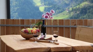 Ein Holztisch mit einer Fruchtschale, einer Weinflasche und einem Weinglas.