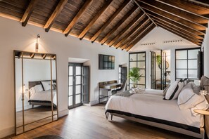 A bedroom with a large bed, a desk, and a mirror.