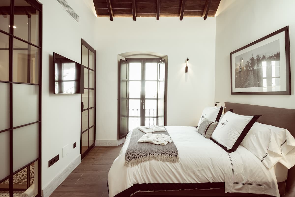 Una camera da letto con un letto grande, una TV montata a parete e un quadro incorniciato sopra il letto.