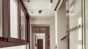 A hallway with a patterned carpet, glass doors with a logo, and a fire extinguisher on the wall. - Hotel Maison Ardois La Ciudadela Marbella (Marbella)