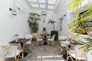 A dining area with a round table, white wicker chairs, and a patterned floor.