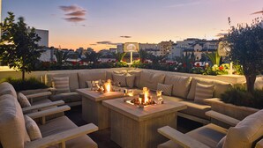 A rooftop terrace with outdoor seating, a fire feature, and a cityscape view at dusk. - Hotel Maison Ardois La Ciudadela Marbella (Marbella)