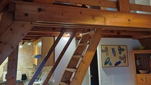 Un escalier en bois mène à une mezzanine où se trouve une plante.