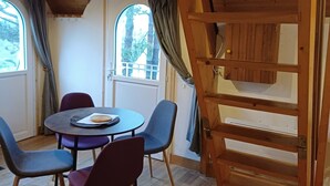 Une pièce chaleureuse avec un plafond en bois, une table ronde entourée de chaises et un lit en mezzanine.