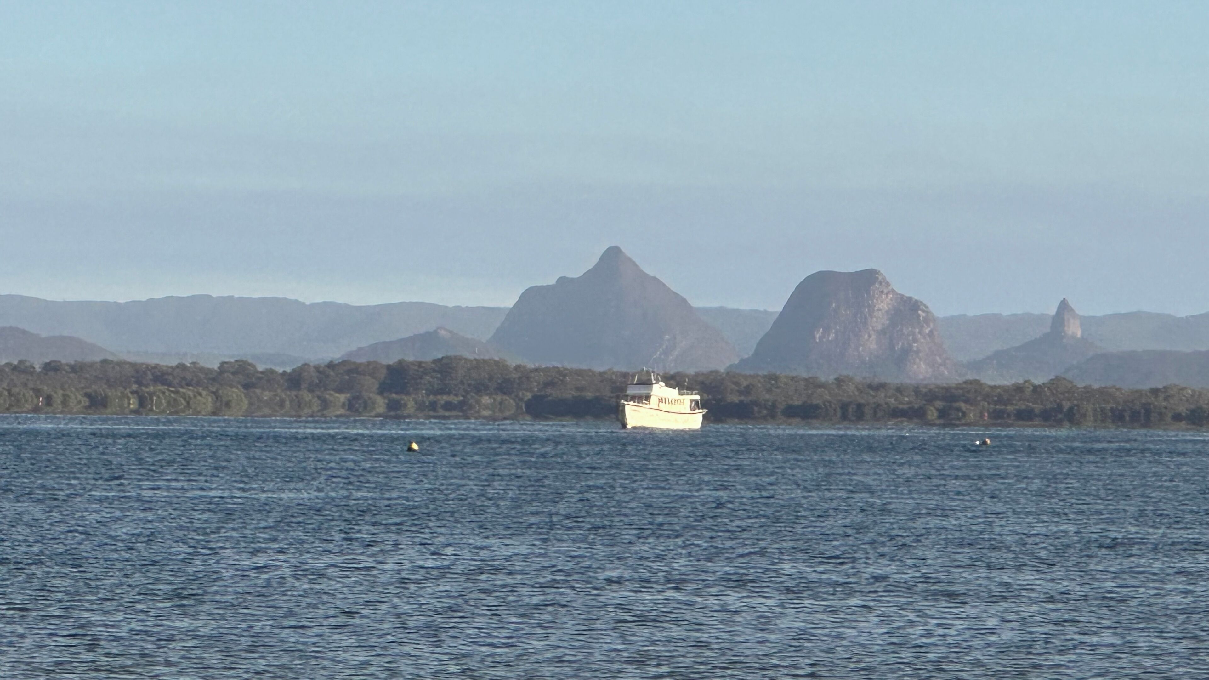 A boat on a calm body of water with mountains in the background.