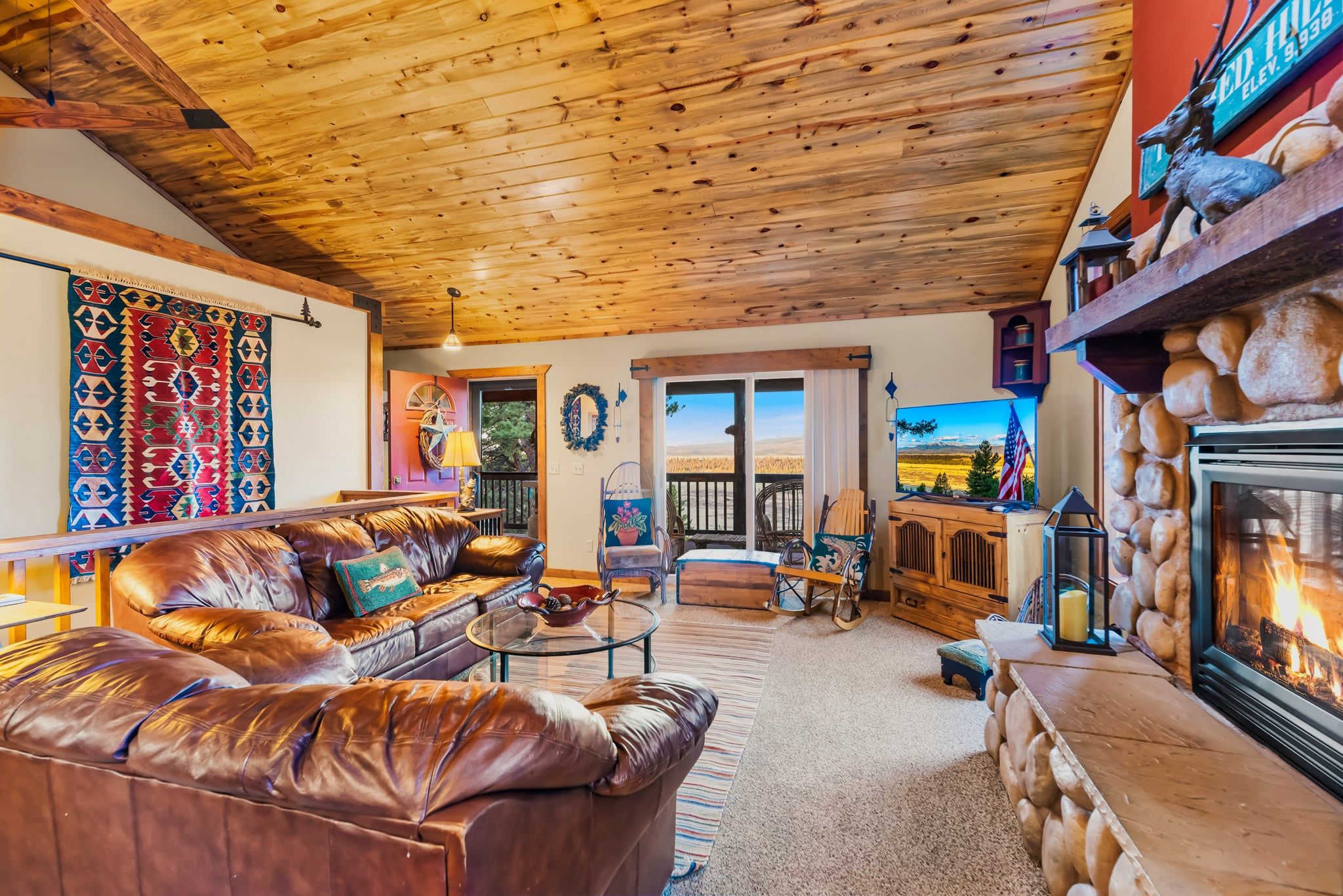 Una sala de estar acogedora con un sofá de cuero, chimenea y un ventanal con vistas panorámicas.