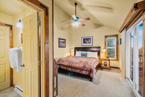 A bedroom with a bed, a ceiling fan, a nightstand, a lamp, and a window.