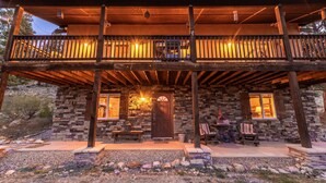 A two-story stone building with a balcony, wooden beams, and a stone fireplace.