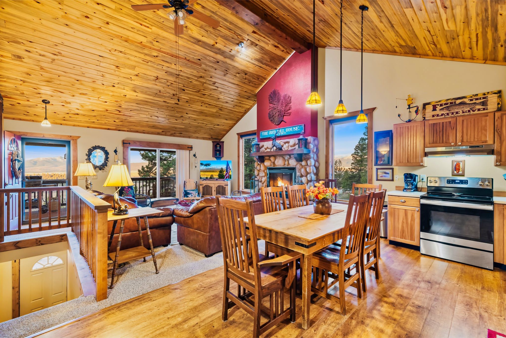 Red Hill House's open-concept main level brings the kitchen, dining area, living room, and stone fireplace together beneath warm vaulted wood ceilings—perfect for keeping the whole group connected.