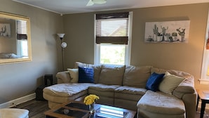 A living room with a sectional sofa, a glass coffee table, and a small side table. - The Steel City Loft  (Bethlehem)