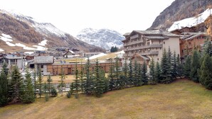 A mountain resort with wooden buildings, snow-capped peaks, and evergreen trees.