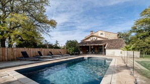 A swimming pool with lounge chairs, a wooden fence, and a house with a tiled roof. - Villa Kundalini - Three Bedroom Villa, Sleeps 8 (Ambres)