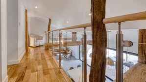 A modern interior with a wooden floor, glass railing, and a view of an outdoor dining area. - Villa Kundalini - Three Bedroom Villa, Sleeps 8 (Ambres)
