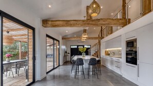 A modern kitchen with white cabinets, stainless steel appliances, and a large island with bar stools. - Villa Kundalini - Three Bedroom Villa, Sleeps 8 (Ambres)