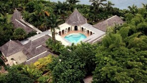 A resort with a central pool, surrounded by lush greenery and palm trees.