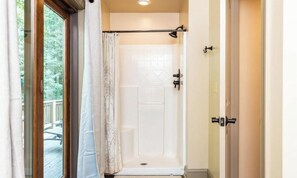 A shower with a glass door, a curtain, and a showerhead.