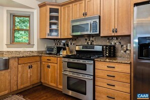 A kitchen with wooden cabinets, a stainless steel stove, a microwave, and a refrigerator.