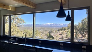 A kitchen with a large window offering a view of mountains and trees.