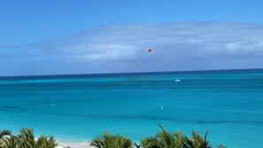 A beach with clear turquoise waters, a boat, and palm trees.