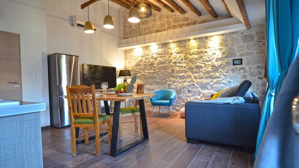 Una cocina moderna con comedor, pared de piedra y vigas de madera en el techo.