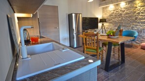 Una cocina moderna con un lavaplatos integrado, un refrigerador y un comedor con mesa y sillas.