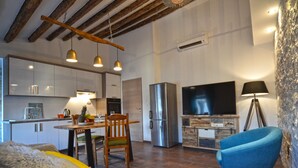 Una cocina moderna con comedor, un sillón azul y un televisor de pantalla plana.
