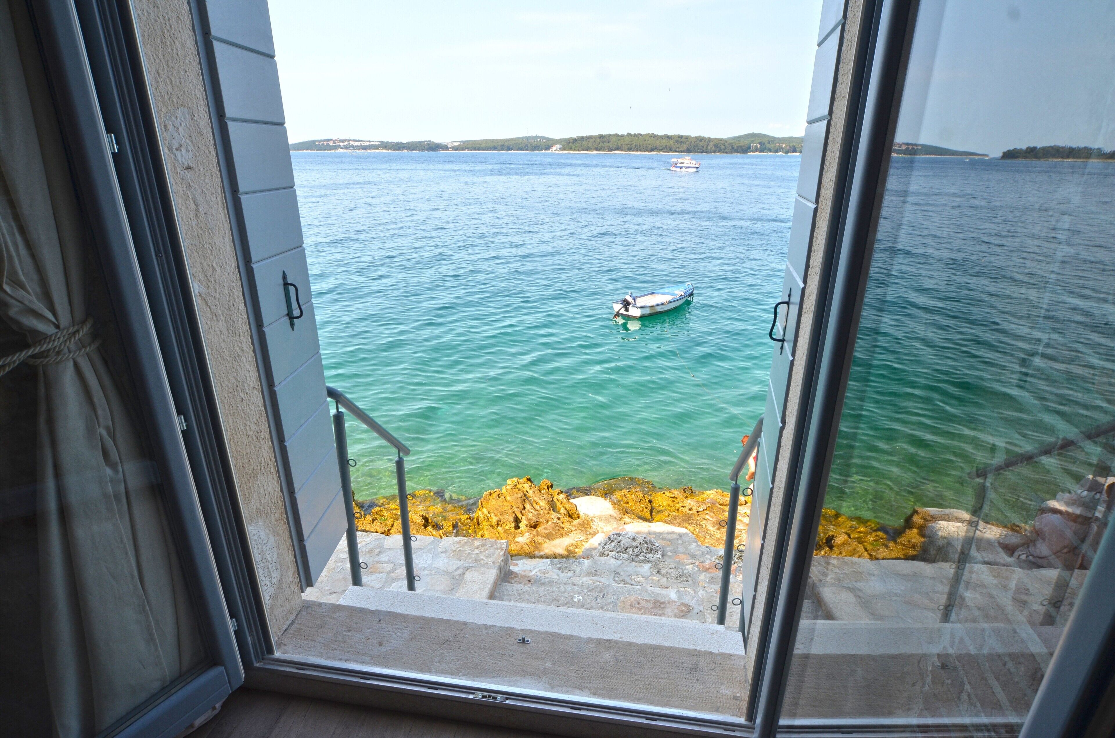 A view from a balcony overlooking a body of water with a boat and distant land.