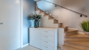 A modern interior with a staircase, a white cabinet with drawers, and a vase with green plants. - Villa Fema Royal with wheerpool and sea view (Rovinj)