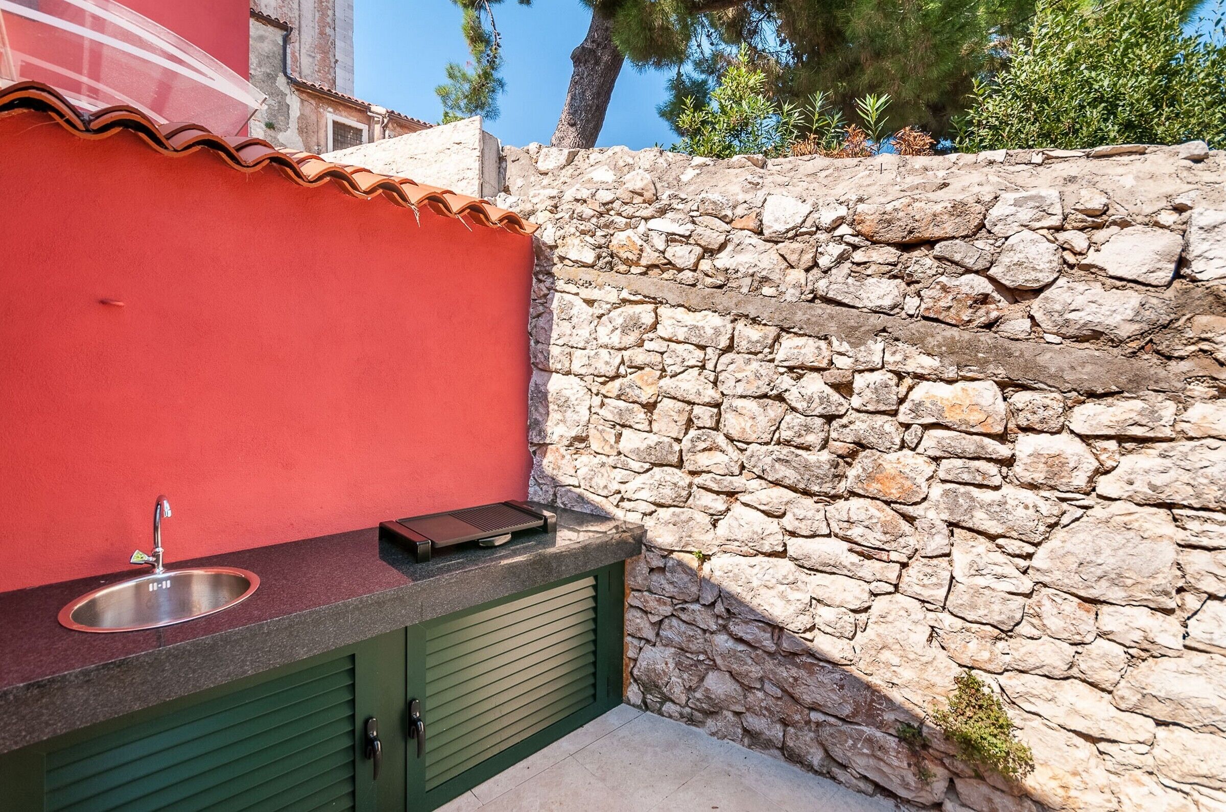 A kitchen with a stone wall, a red wall, and a green door.