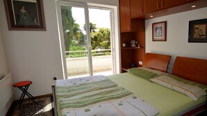 A bedroom with a bed, a small table, a chair, and a sliding glass door leading to a balcony. - Alma Borik Apartment with balcony (Rovinj)