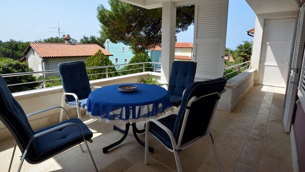 A balcony with a round table and four chairs, overlooking a residential area with houses and trees. - Alma Borik Apartment with balcony (Rovinj)