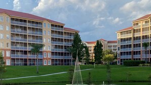 A multi-story hotel with balconies, a central water feature, and a well-maintained lawn.