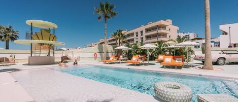 A pool area with lounge chairs, a water feature, and a building in the background.