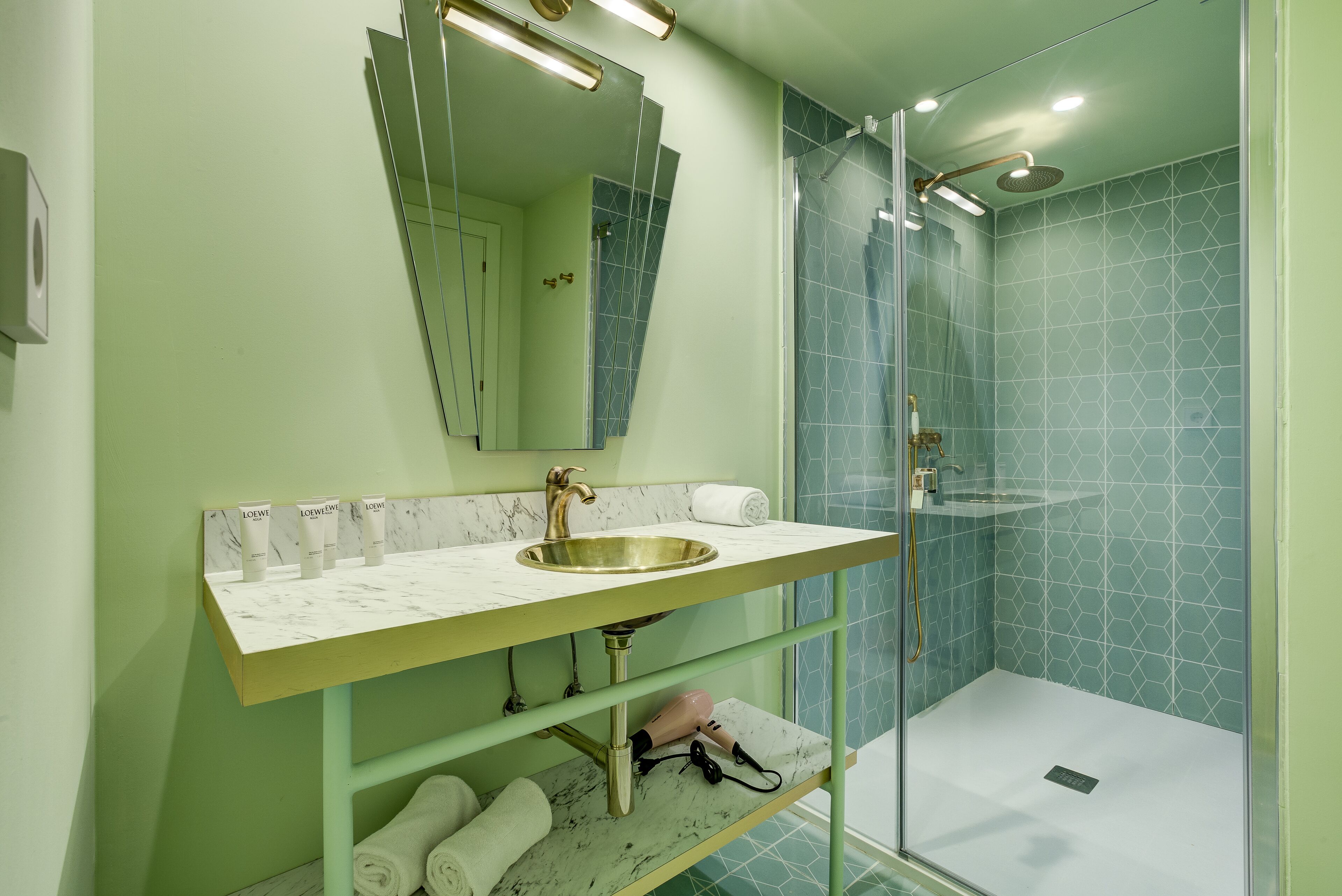 A bathroom with a marble sink, a glass shower enclosure, and a mirror above the sink.