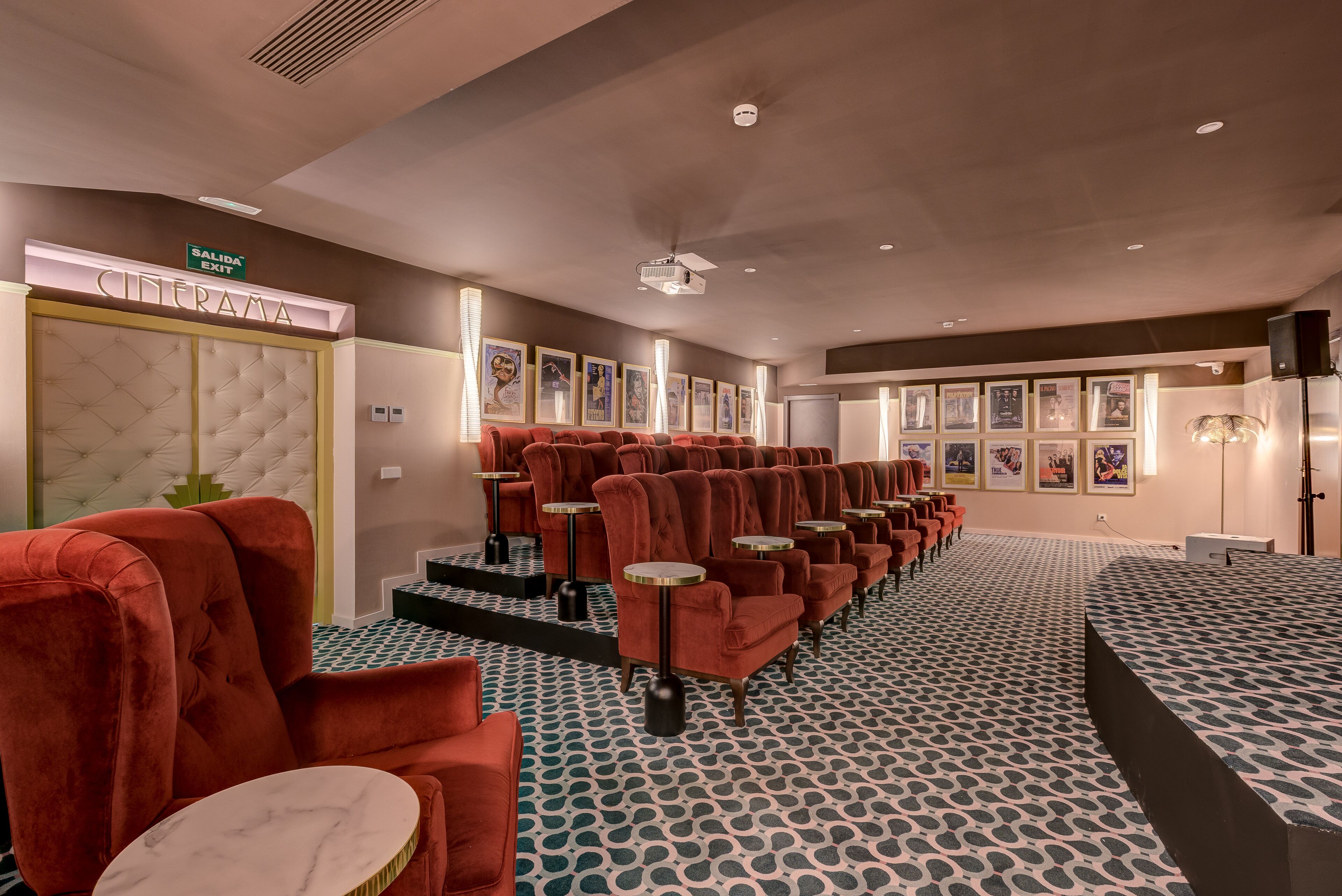 A cinema with red velvet seating, a 'CINEMA' sign, and framed posters on the wall.