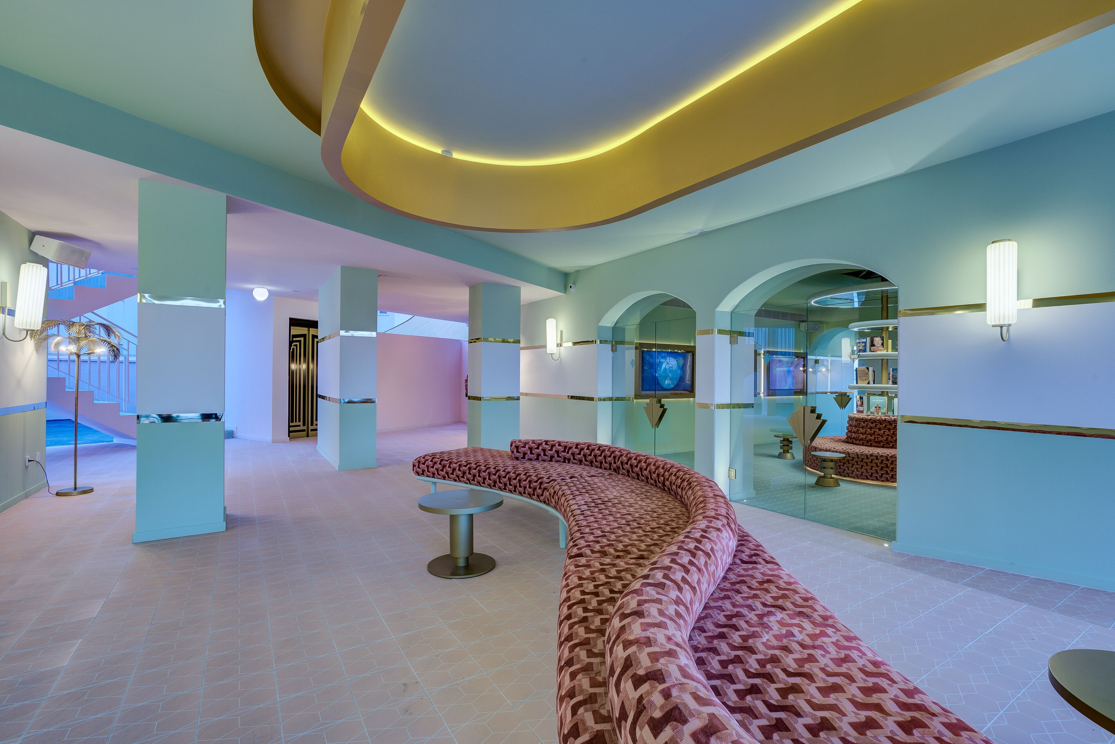 Ein modernes Interieur mit einer gebogenen Sitzecke, einem kleinen Tisch und einer Treppe, die zu einer oberen Ebene führt.