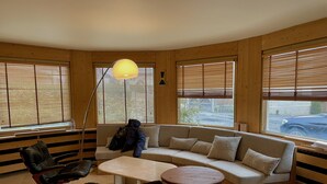 Une pièce chaleureuse avec un décor intérieur en bois, un canapé, un fauteuil, une petite table et une lampe sur pied.