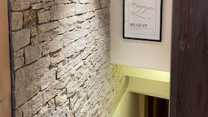 Une pièce avec un mur en pierre, une carte encadrée des Alpes françaises et un plafond en bois.